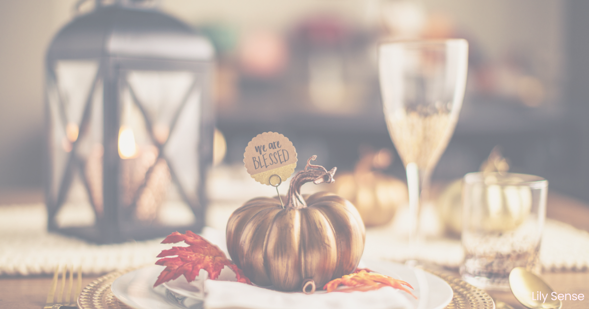 A photo of a Thanksgiving table after the meal with a golden pumpkin and a note attached saying we are blessed.
